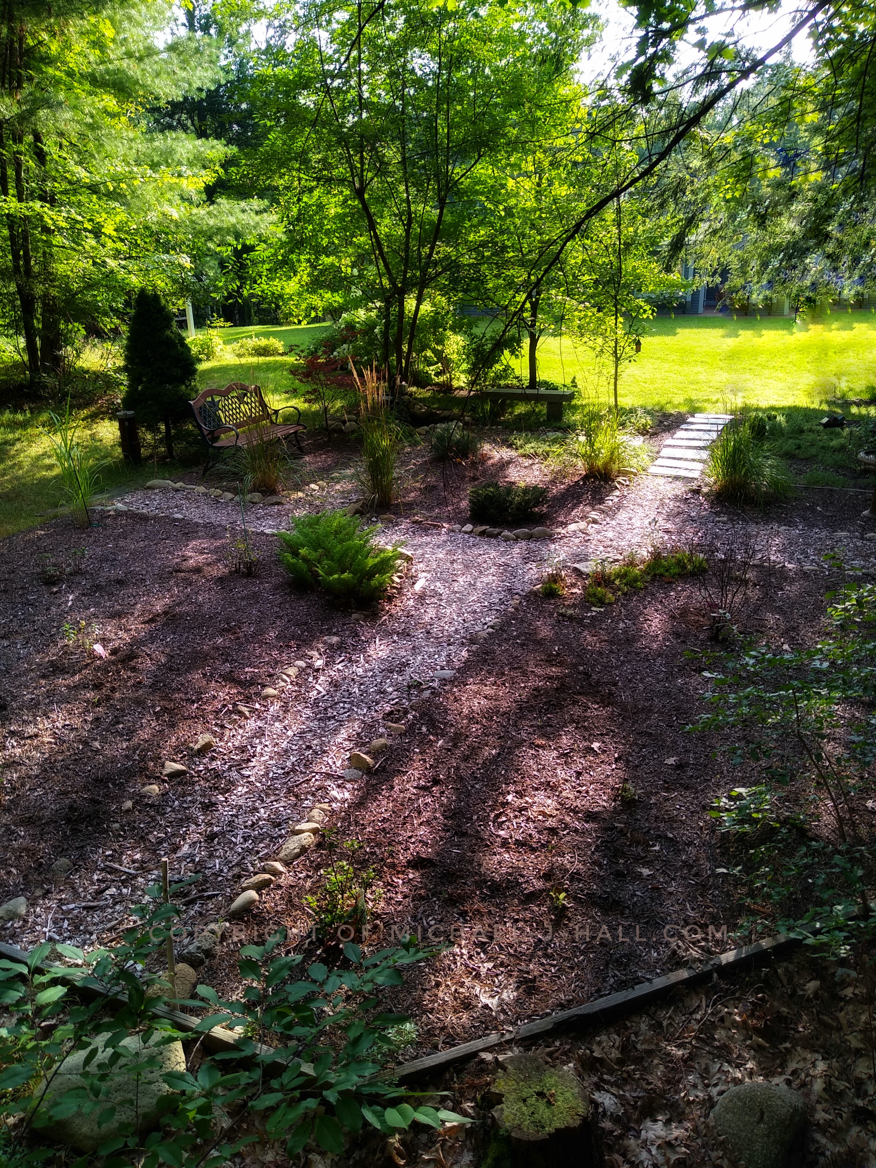 Stepping out of the woods there are so many options to consider, a patter over the slates to the open grass lawn, or a journey down a side path to a park bench, or a spot in the shade on a granite bench by a miniature pond, or a turn to the right and visit a birdbath.